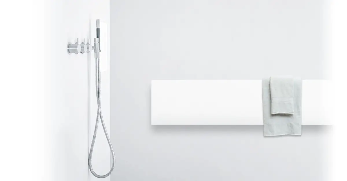 Panel radiante blanco horizontal con una toalla colgada, junto a una ducha de mano