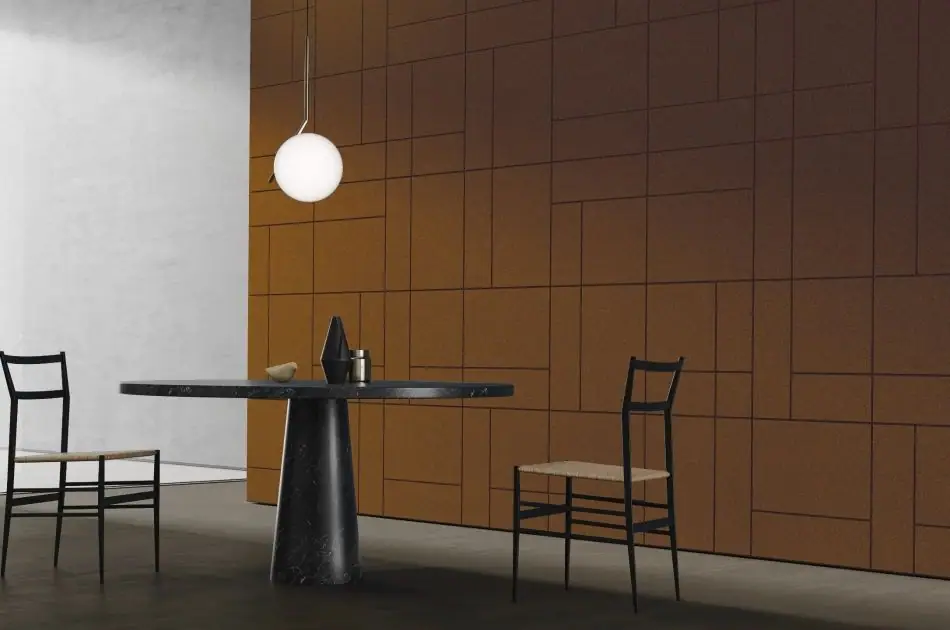 Mesa redonda de mármol negro y dos sillas ante una pared de placas de corcho Modular en tono cálido
