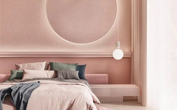 Dormitorio en tonos rosa con la pared del cabecero revestida con paneles de relieve lineal y un gran círculo retroiluminado.