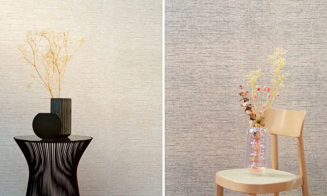 Two walls with woven-paper textured wallpaper in light tones, with a black side table and a wooden chair