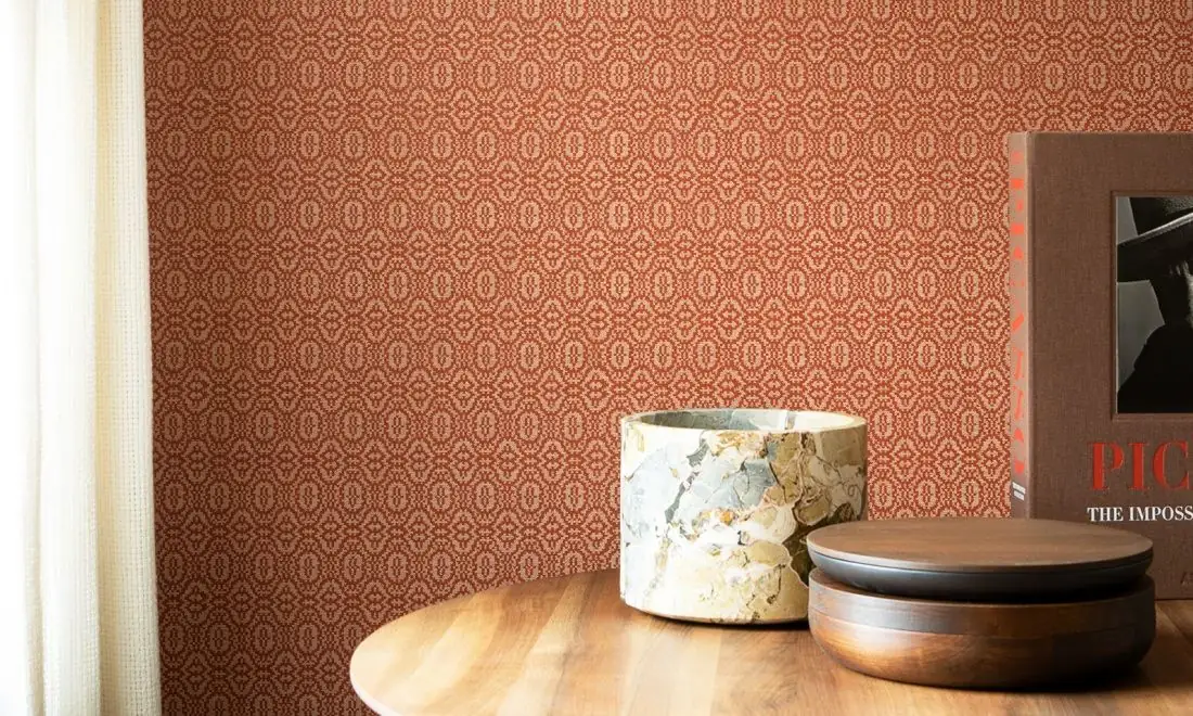 Wall with wallpaper of closed geometric motifs in terracotta tones and a wooden table with marble and wood containers