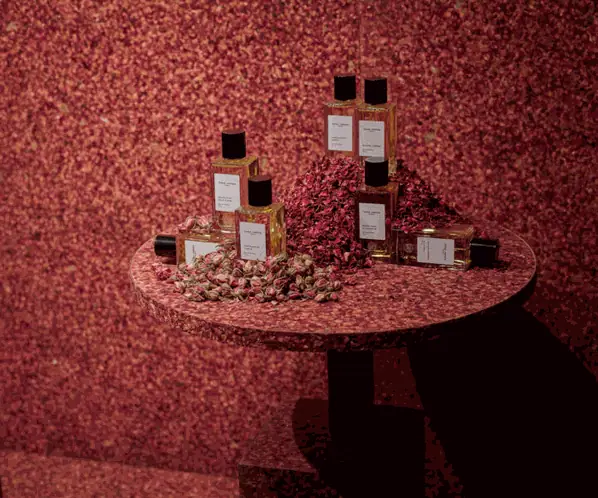 Wall and table covered with pressed rose petals, with perfume bottles on the table