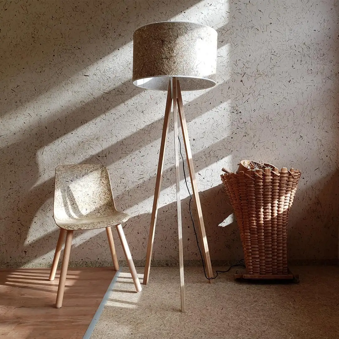 Chair, floor lamp and wall covered with hay surfaces, next to a wicker basket