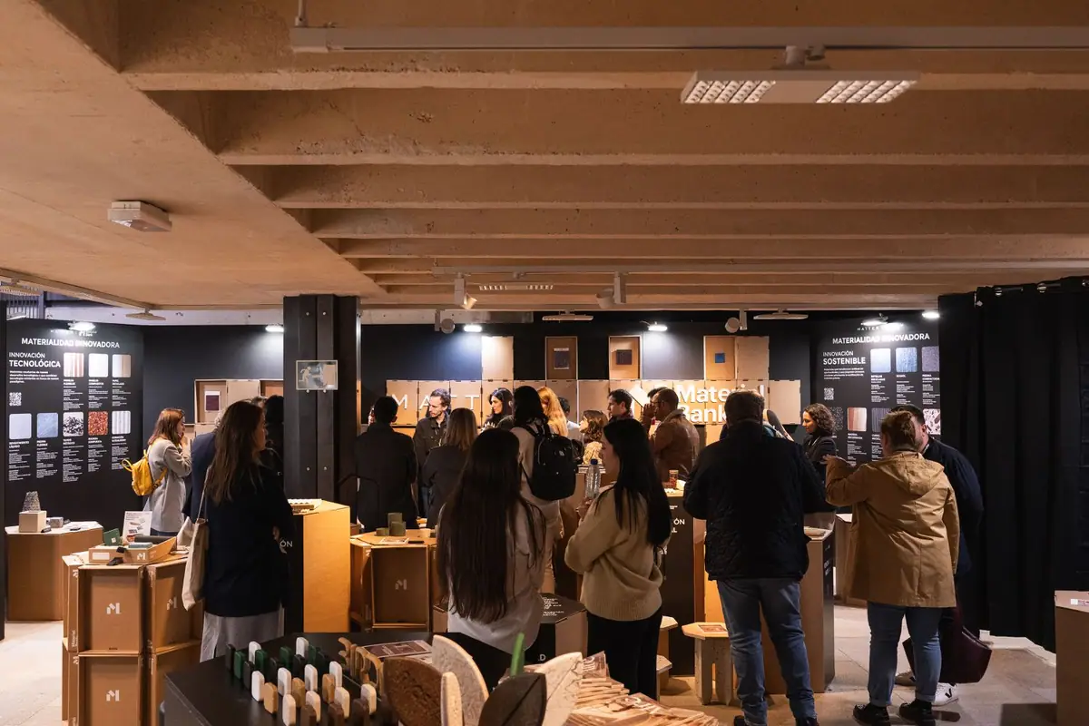 Visitors walk through the Innovative Materiality space, with black panels on both sides and samples on cardboard modules