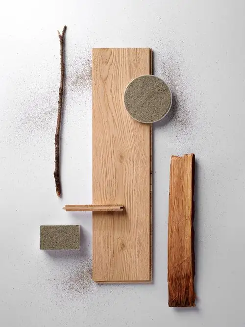 Light oak board on a white background, with a grey stone disc, bark and a branch