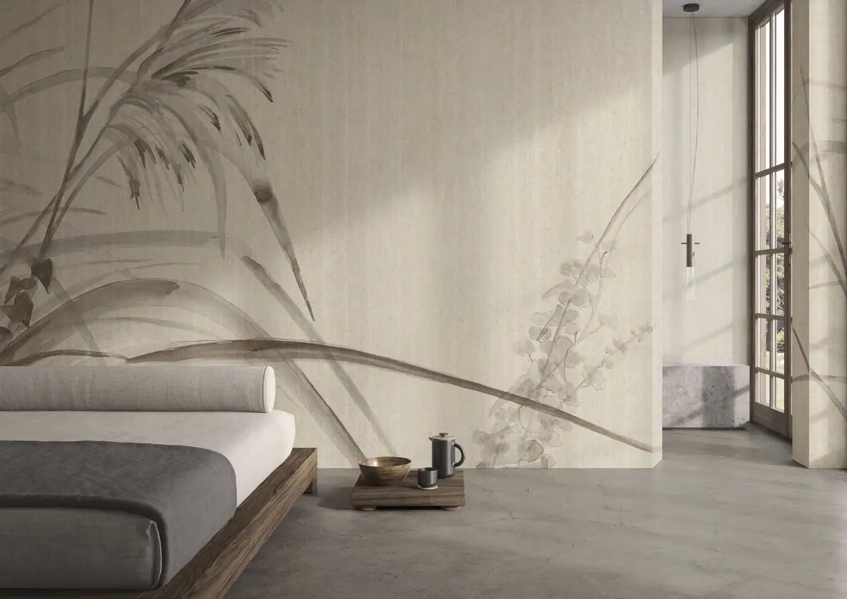 Dormitorio con cama baja de madera ante una pared revestida con gramíneas y flores en tonos grises sobre fondo de lino.