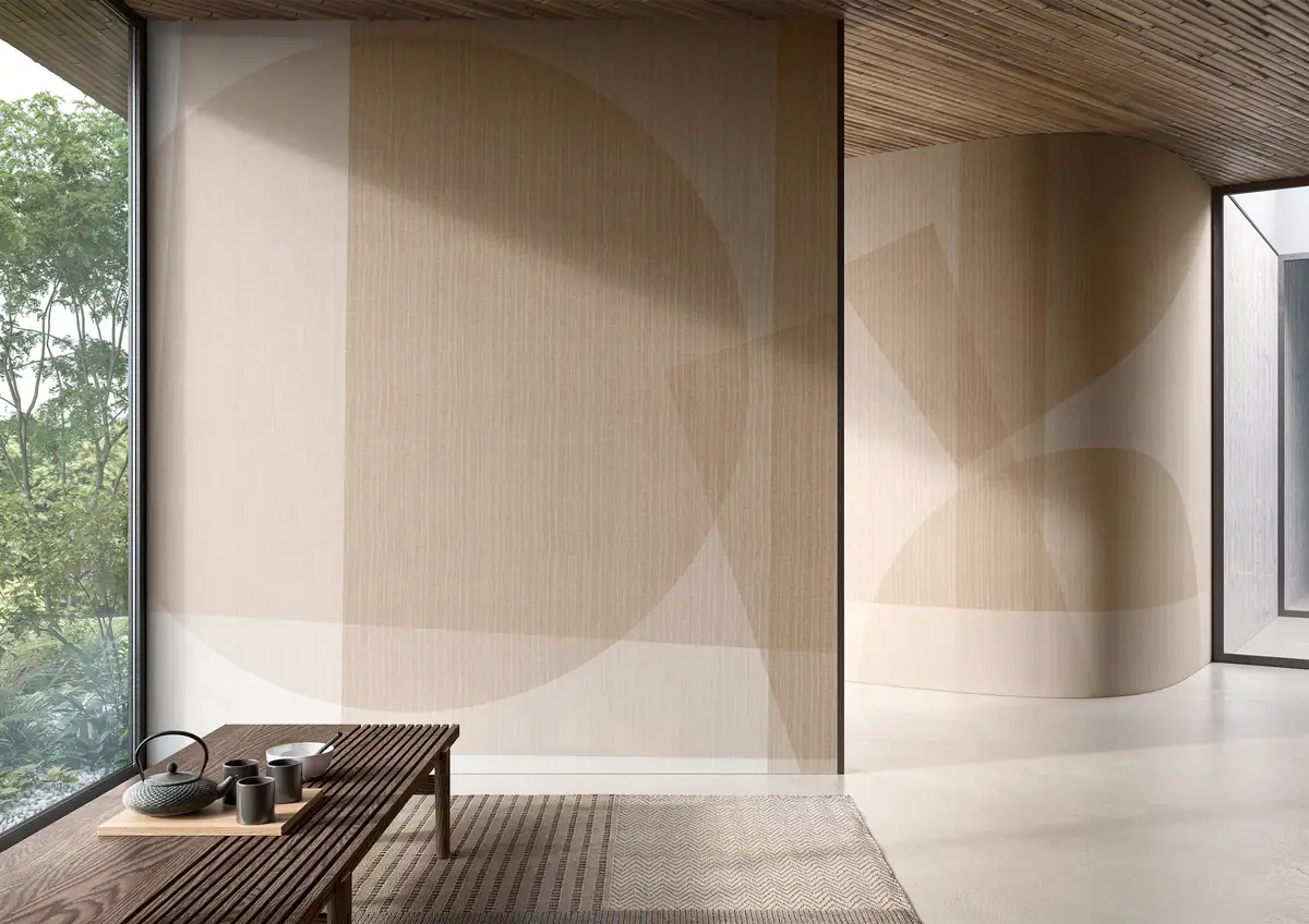 Sala con banco de madera y servicio de té ante paredes revestidas con grandes círculos y planos geométricos en tonos arena.