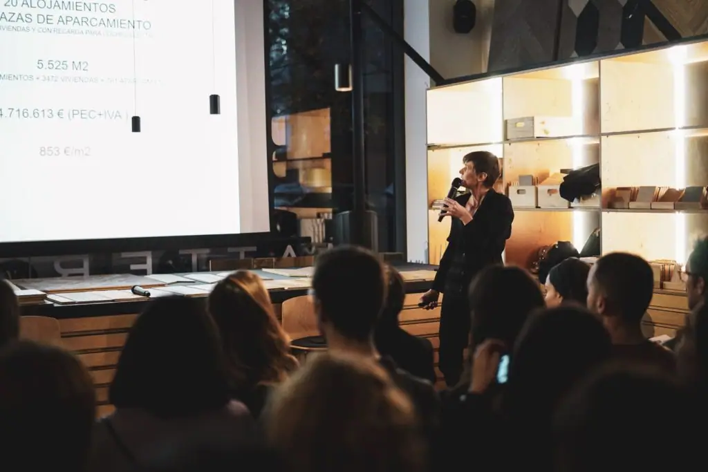 Judith Leclerc speaks to the audience beside a screen showing data on the 22@ building