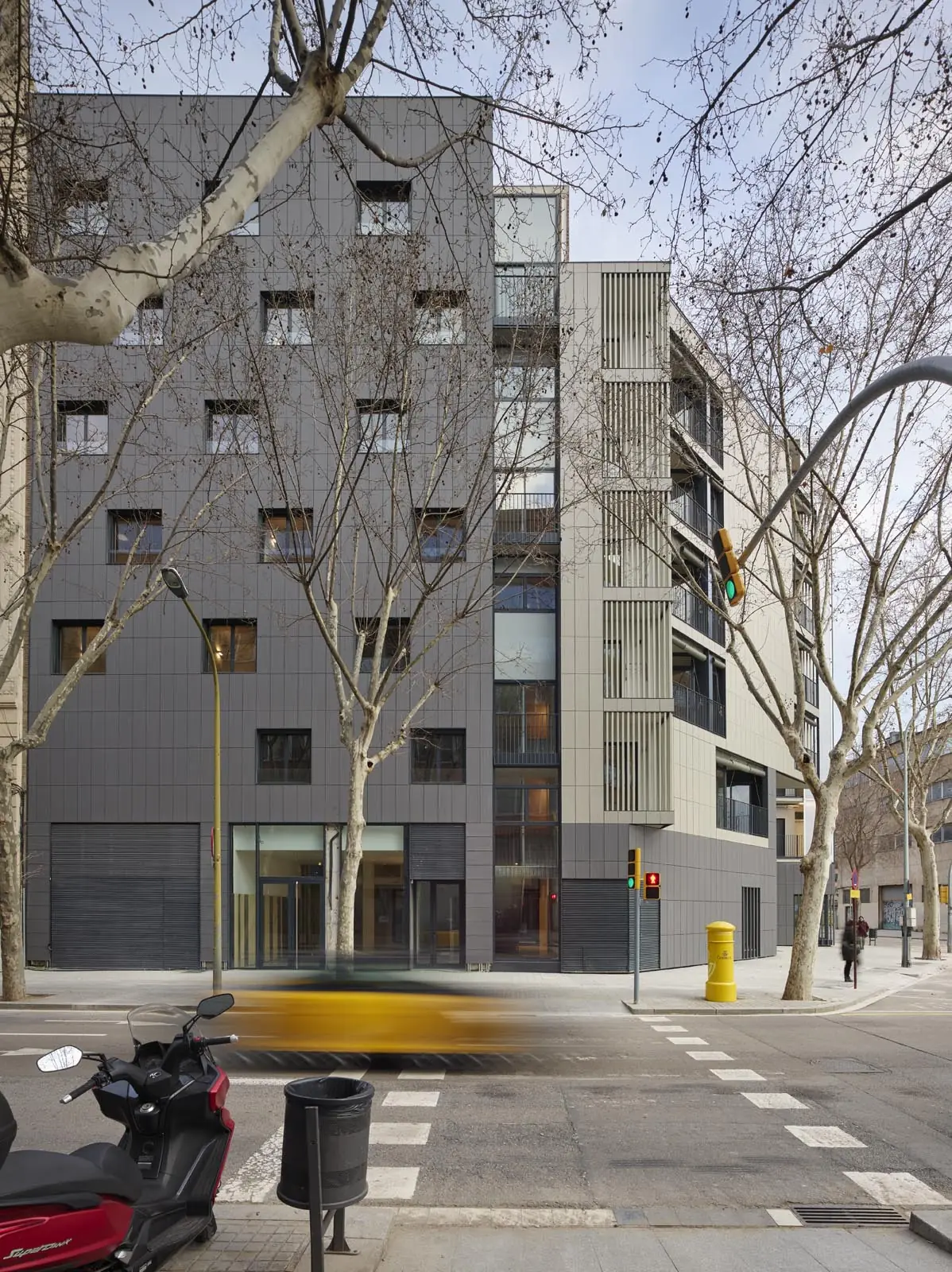 Façade of the Coll-Leclerc housing building on a corner in 22@, with trees on the pavement