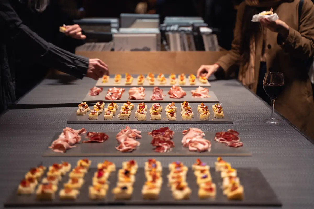Bandejas de canapés y embutido servidas sobre una mesa de materiales