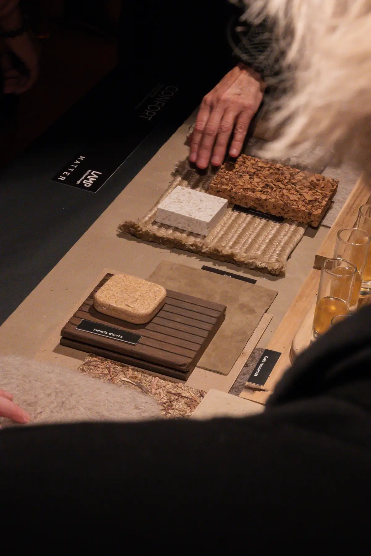 Mano tocando muestras de corcho, piedra y madera sobre un tablero de materiales con el logotipo de Matter