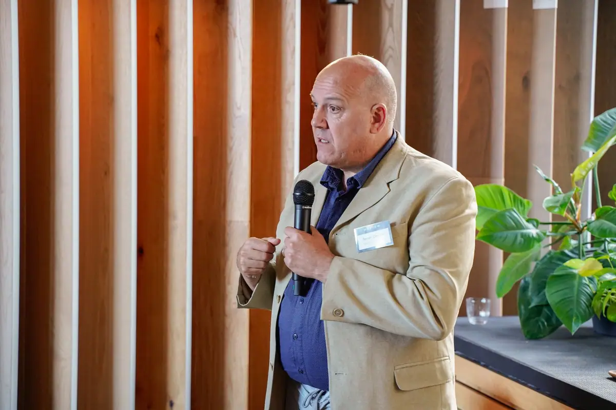 Ferran Caudet speaking into a microphone against a background of wooden slats