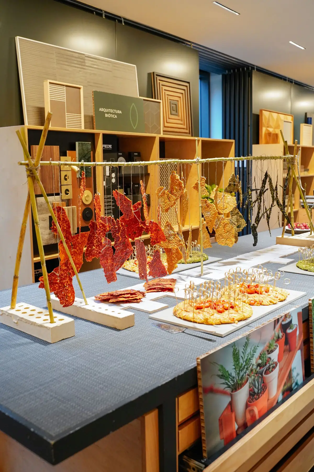 Table with vegetable sheets hanging from a cane frame, next to material samples