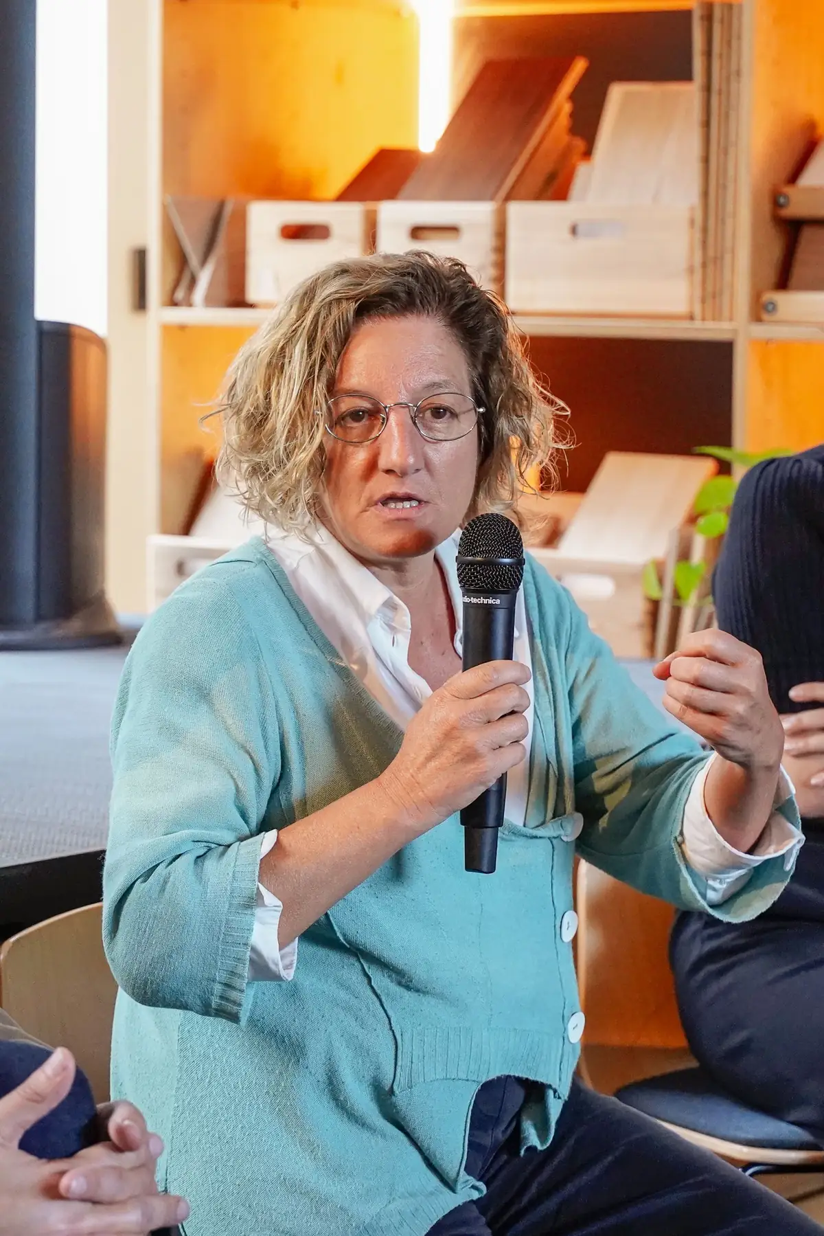 Speaker seated among the audience talking into a microphone