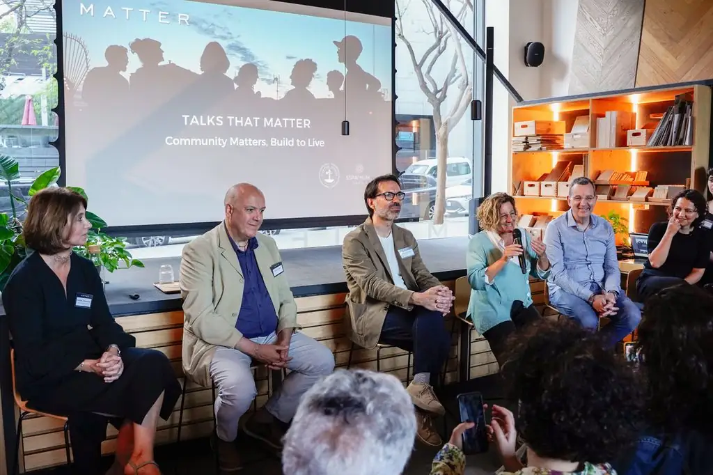 Speakers seated in front of the Talks That Matter: Community Matters, Build to Live projection