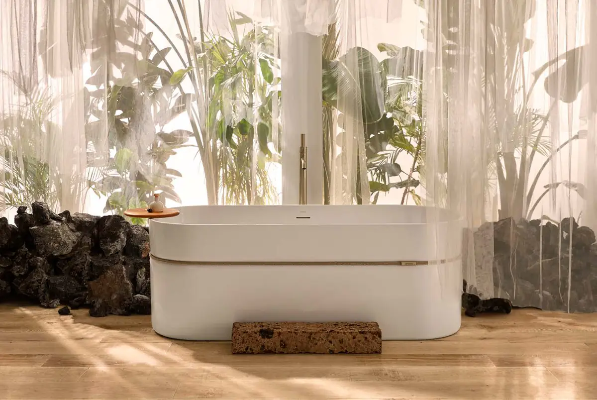 Bañera exenta blanca rodeada por una cuerda, entre plantas y rocas volcánicas