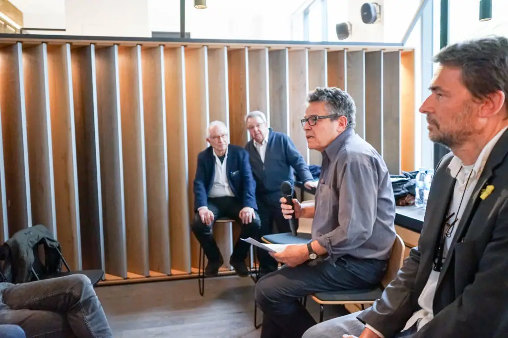 Four speakers seated in front of the timber panels at Matter Barcelona, one of them holding a microphone and papers