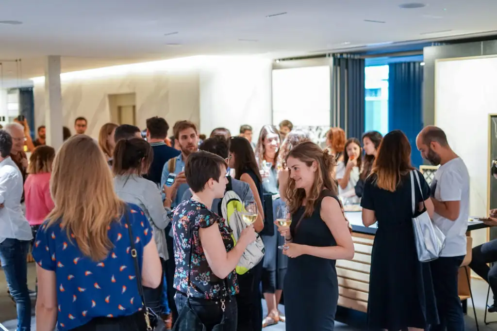 Grupo de asistentes de pie charlando durante el aperitivo