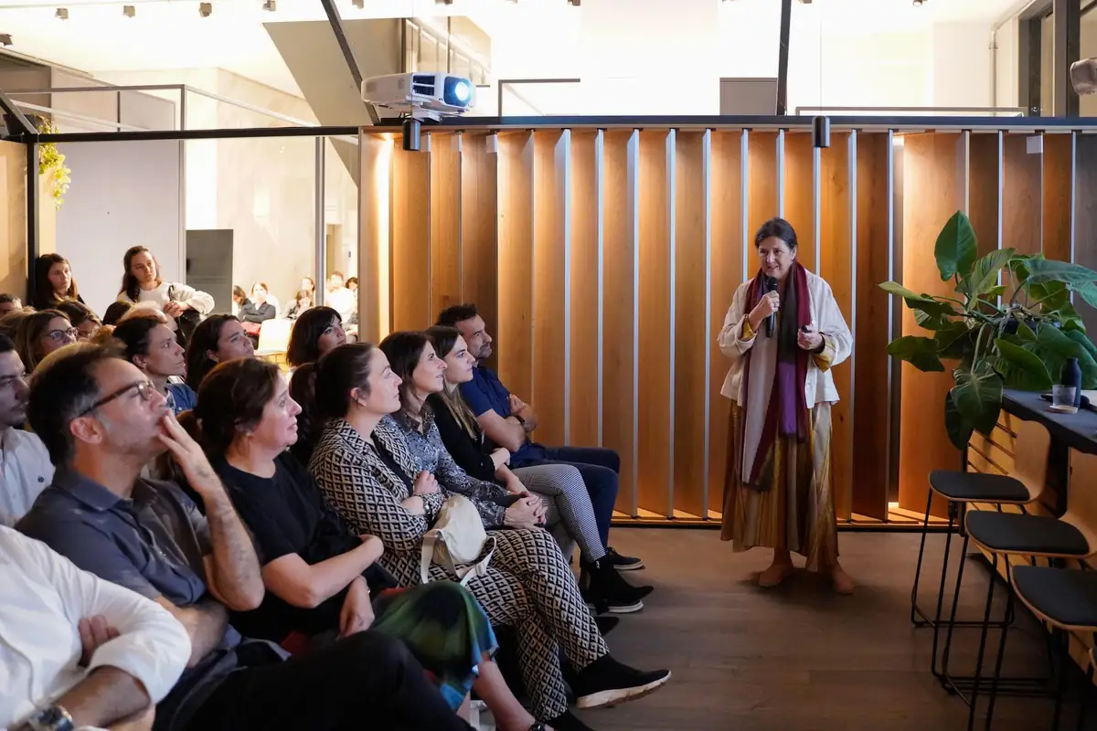 Una ponente con fular habla ante el público junto a las lamas de madera de la sala