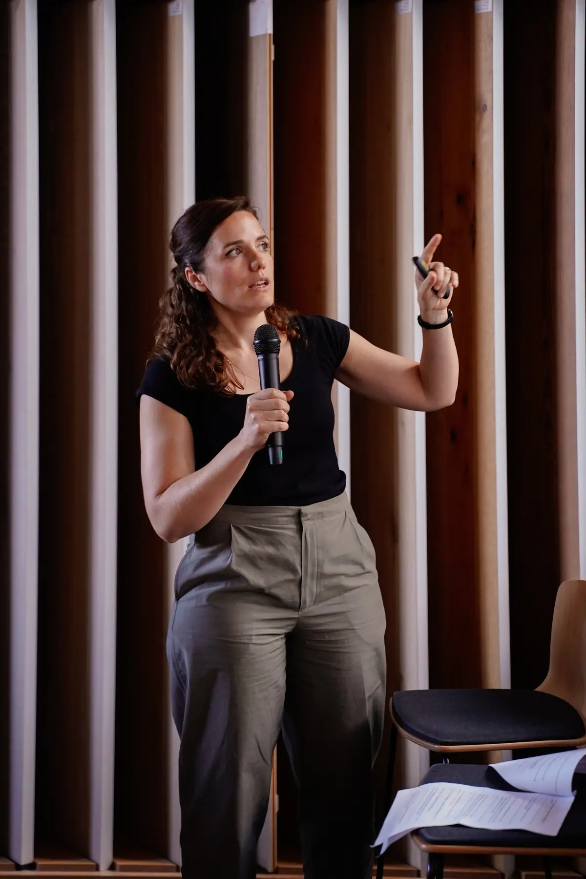 Irene Antonijoan, holding a microphone, points to the screen during her presentation