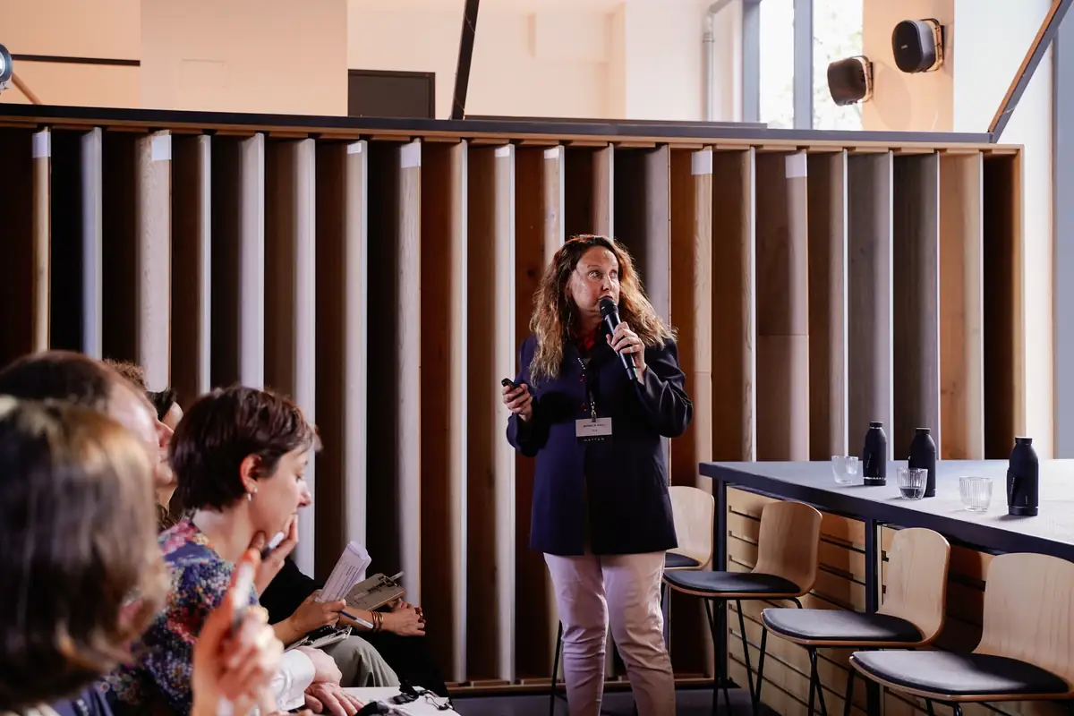 Mónica Grau, standing with a microphone, presents FEDE's collections to the audience