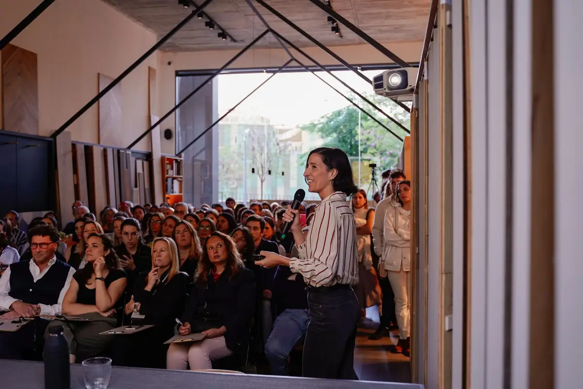 Lucía Millet speaks into a microphone in front of the audience that fills the room