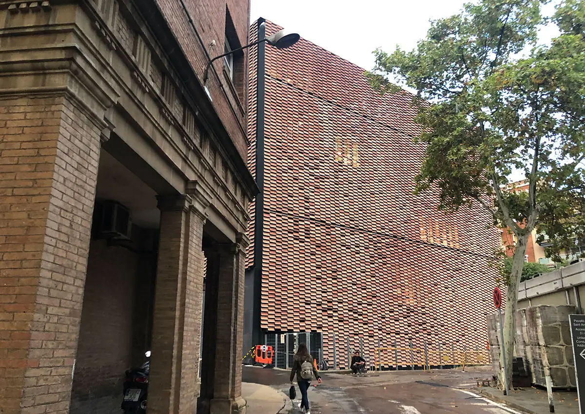 Ceramic lattice facade of the Sant Pau Research Institute beside a historic brick building