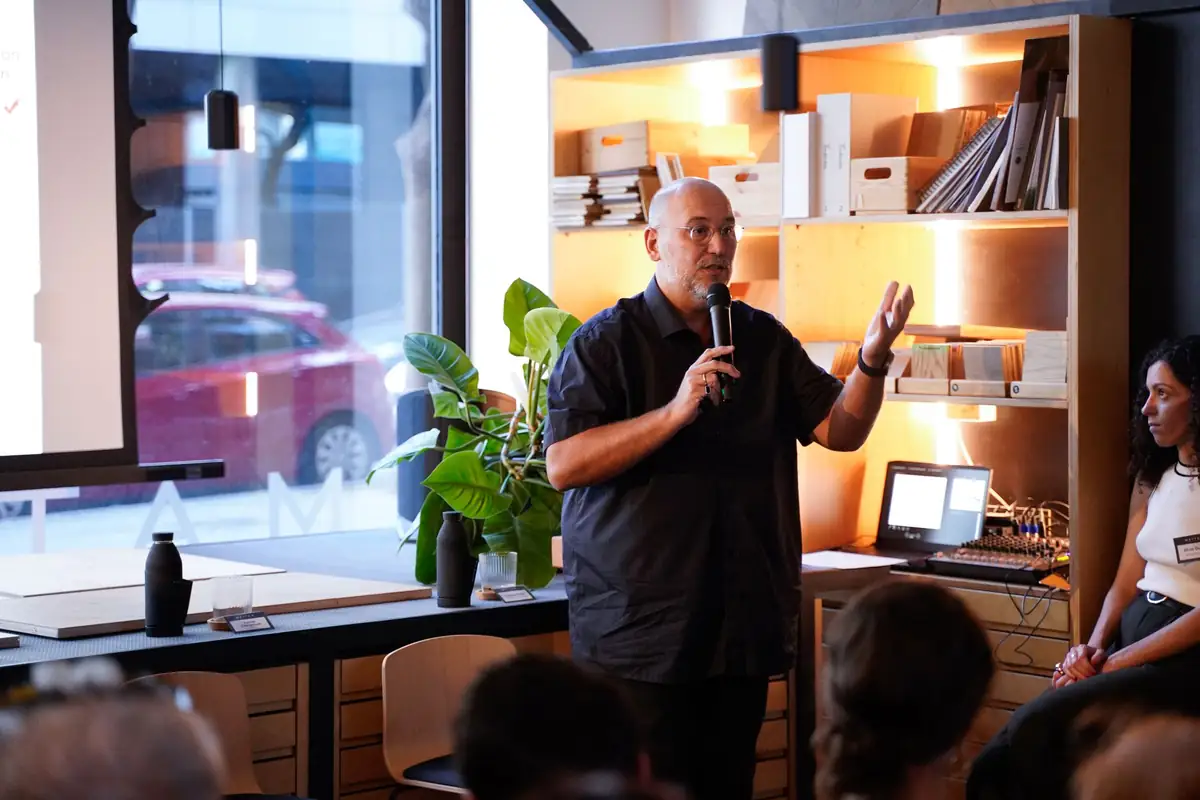 A speaker talks into a microphone beside a shelf of material samples