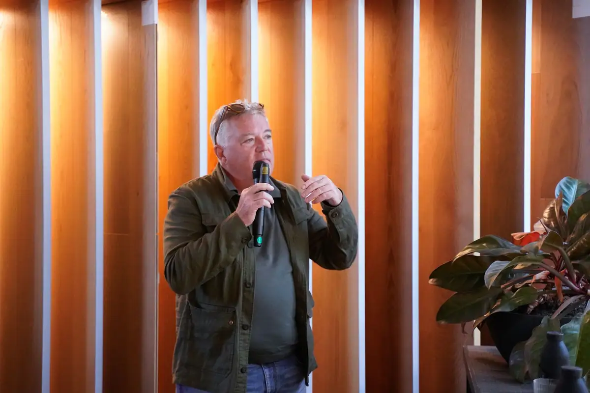 Xavier Claramunt speaks into a microphone in front of timber slat cladding