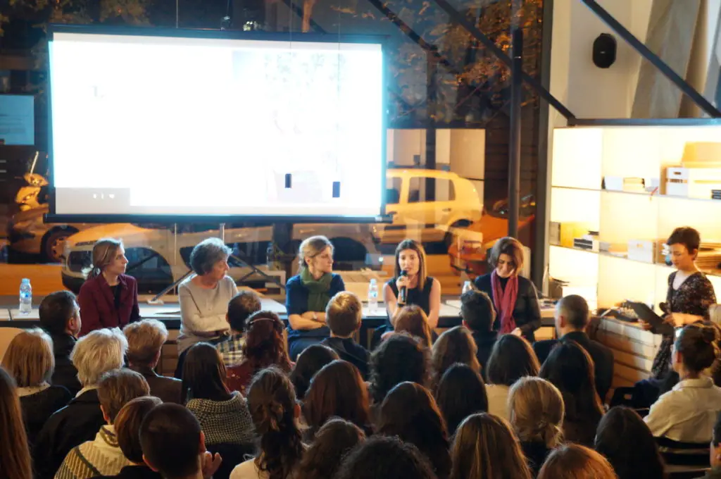 The speakers seated in front of the screen while one of them addresses the audience in the Sala Matter