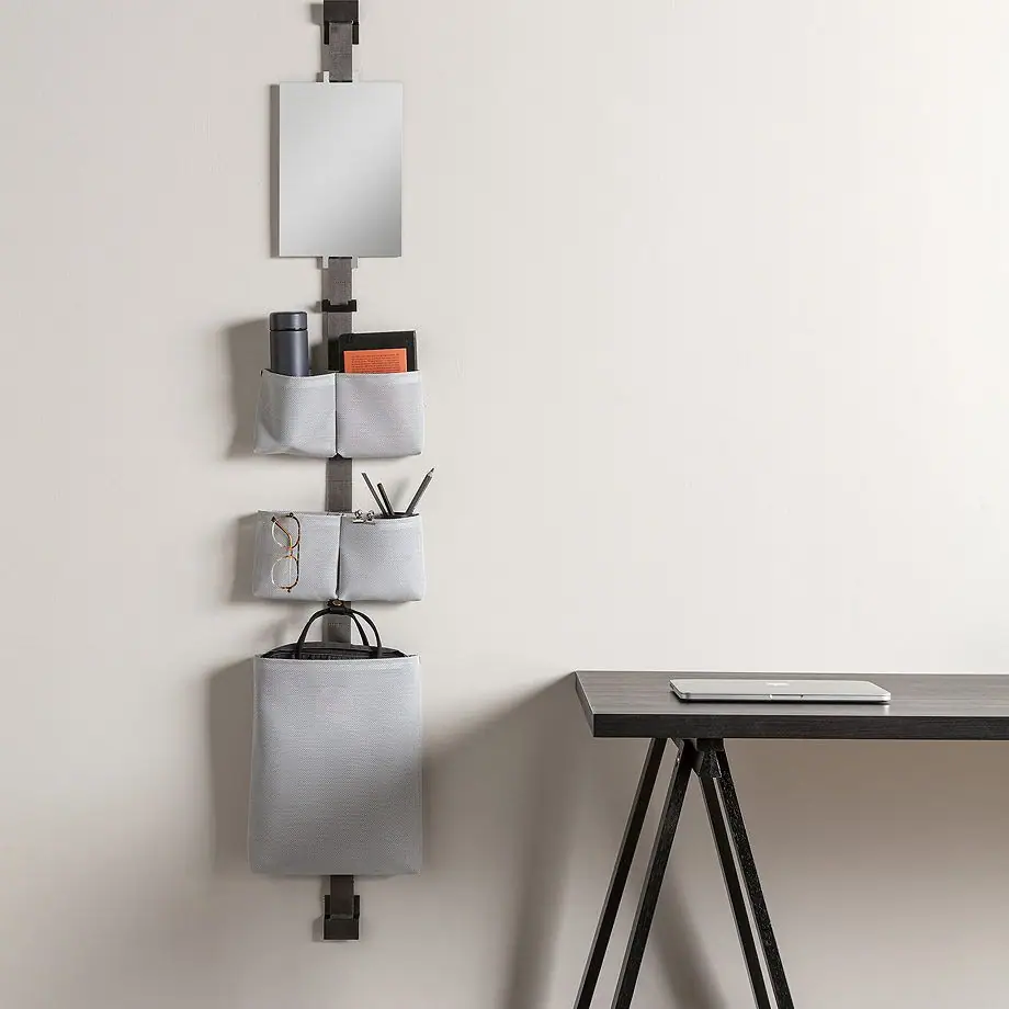 TAPE STORAGE strap on the wall of a study, with a rectangular mirror, grey pouches and a large bag next to a work desk