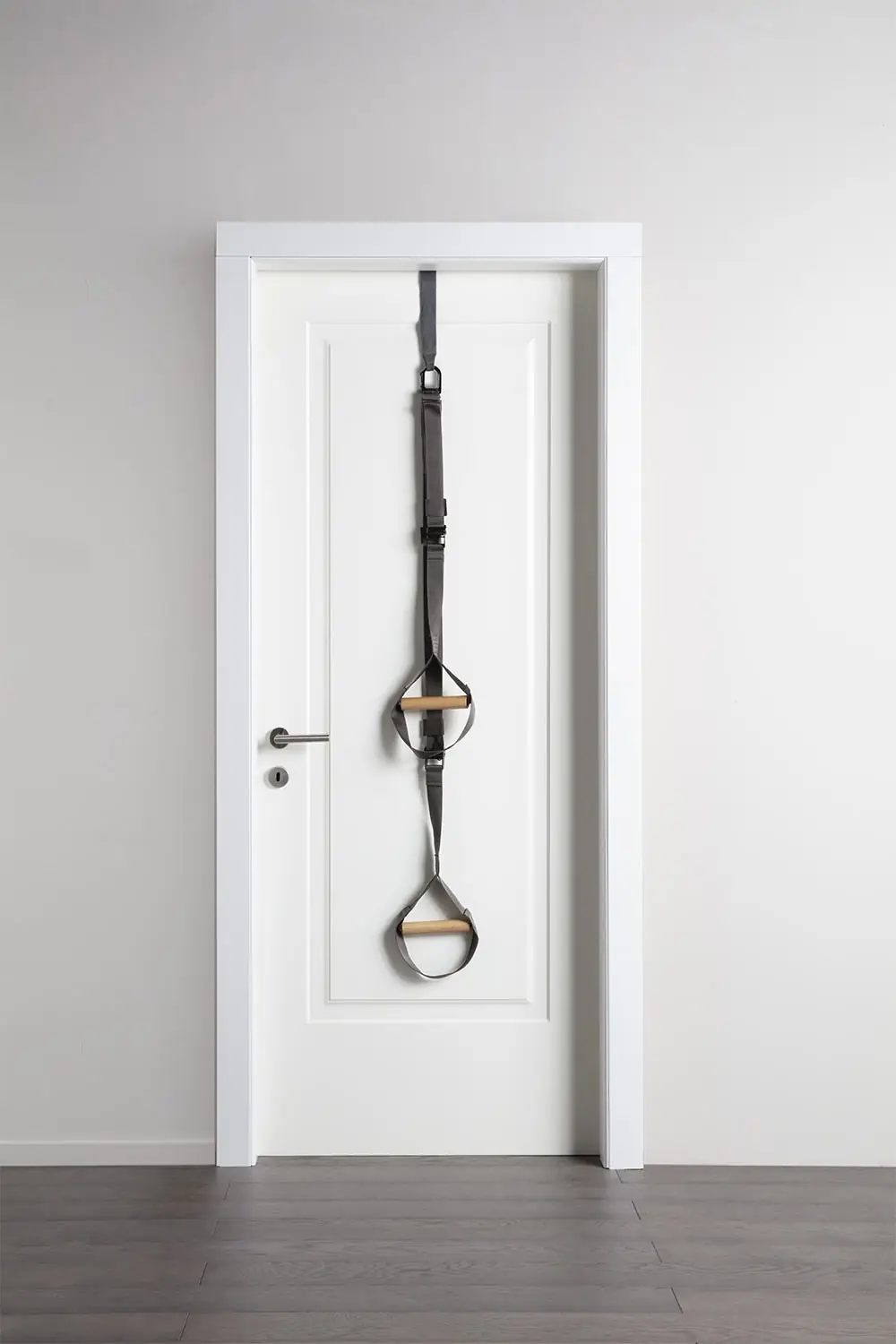 TAPE FIT training strap hanging from a white door, with two beech handles