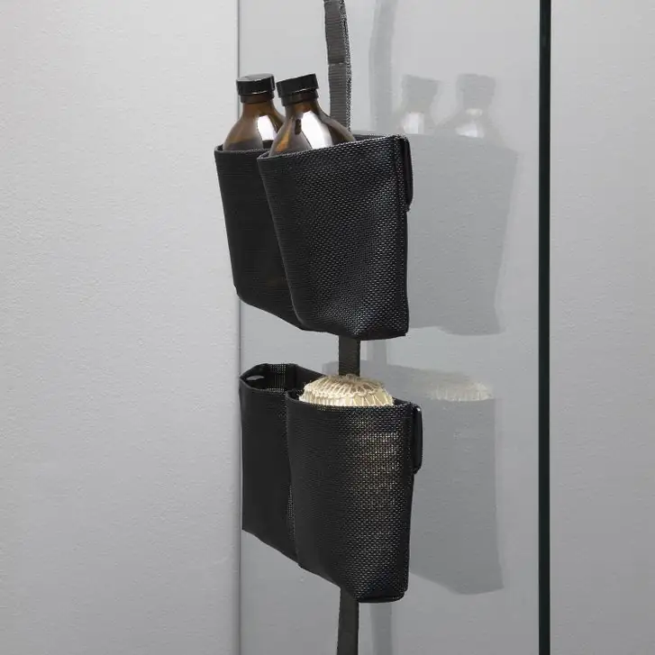 TAPE SHOWER strap on the glass of a shower with two black double pouches holding bottles and a sponge