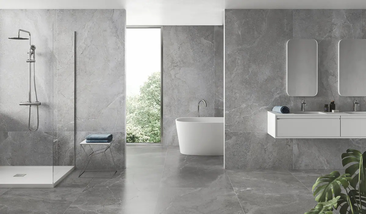 Bathroom with walls and floor in large-format grey veined stone-effect porcelain, a walk-in shower and a freestanding bath
