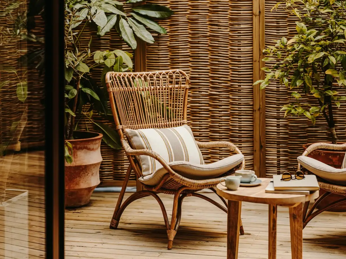 Rattan armchair with a striped cushion on a terrace with a wicker enclosure and plants