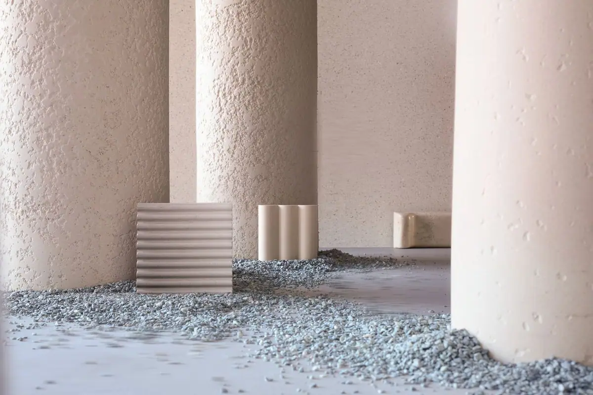 Columns with a cementitious texture and fluted pieces on a bed of gravel