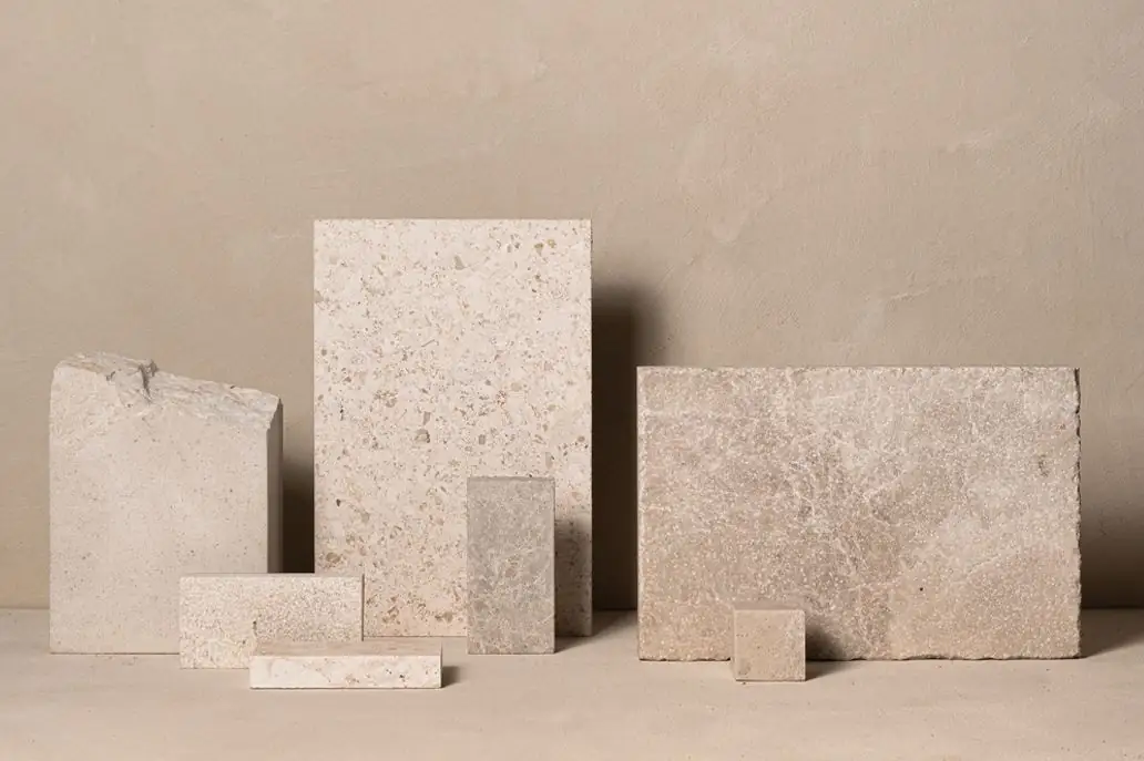 Pieces of light limestone in different formats and finishes on a beige surface