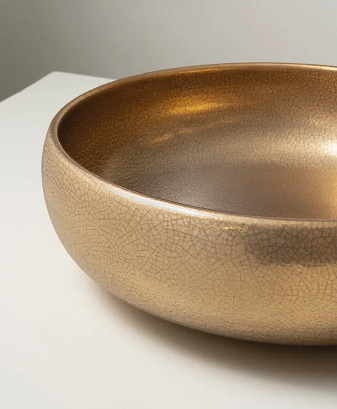 Round countertop basin with a glossy gold finish and fine crackle on a white surface