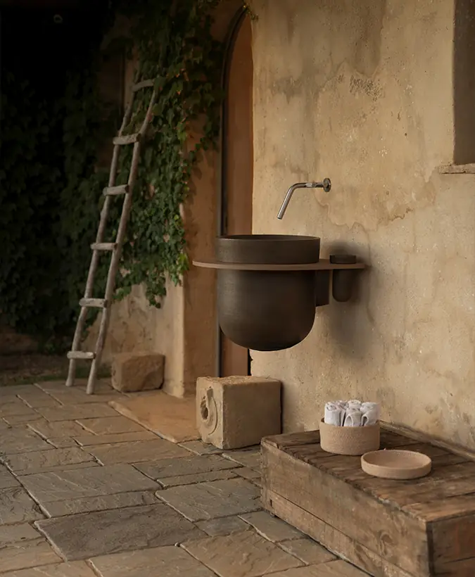 Dark ceramic wall-hung washbasin with a light top fixed to a stone wall next to a door