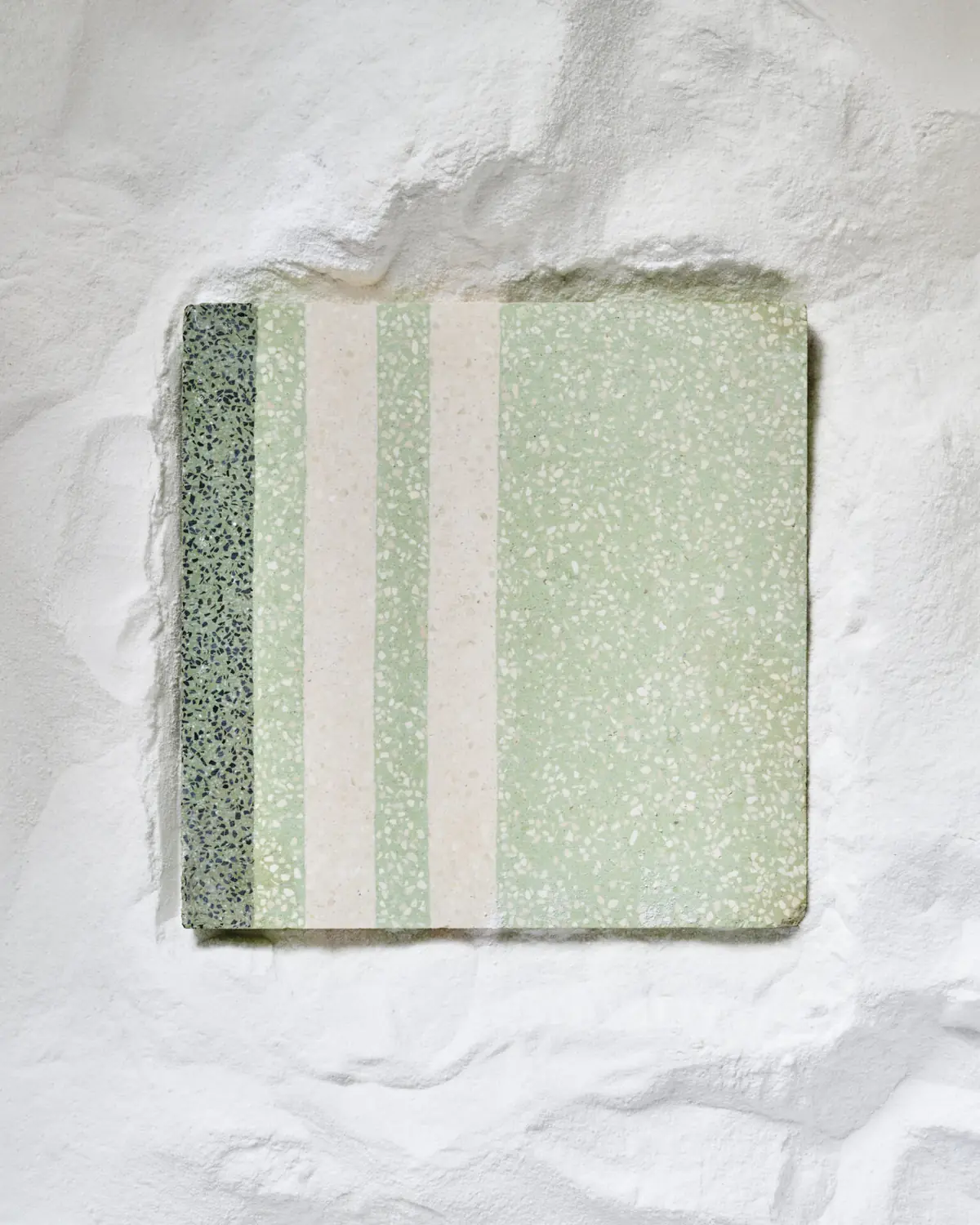 Square graniglia tile with green and white stripes and visible marble grains