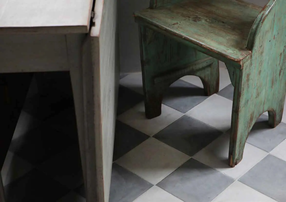 Chequerboard floor of white and grey tiles under a green wooden chair