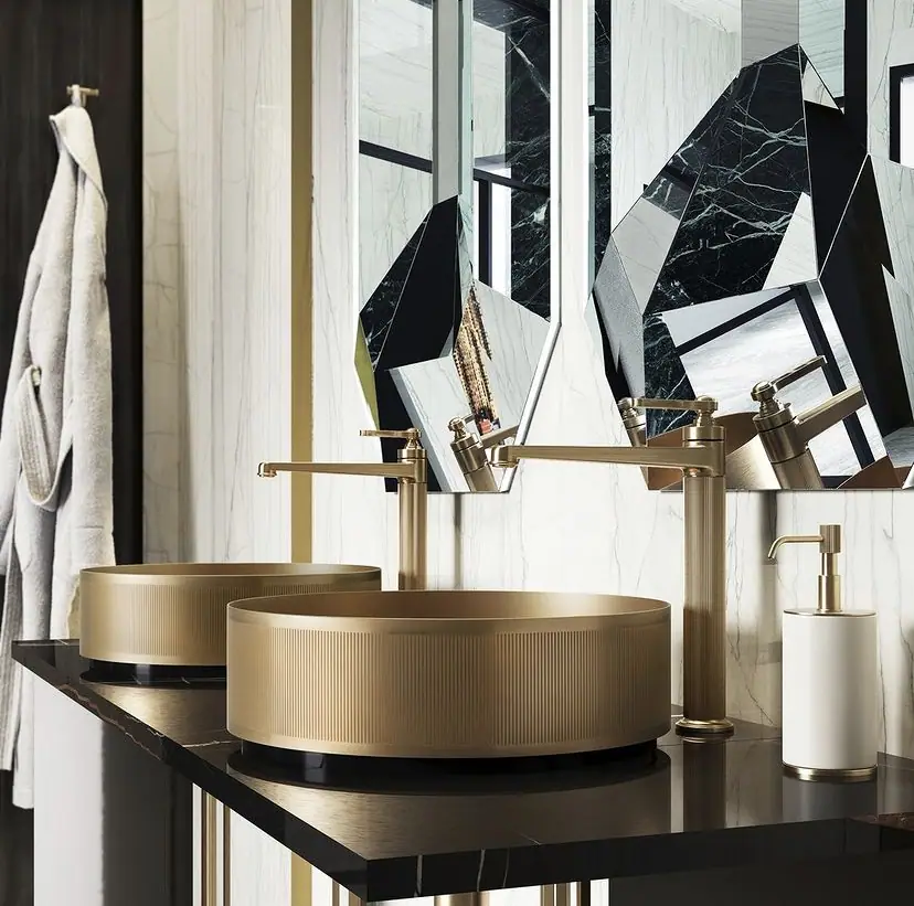 Two round fluted countertop basins in a bronze finish on a black marble top, with tall Venti20 mixers and faceted mirrors