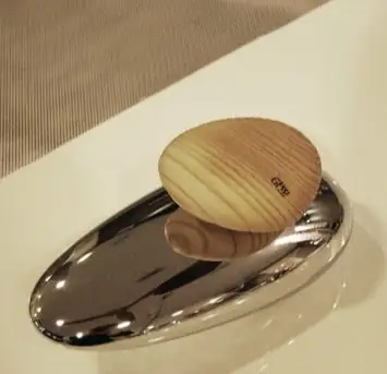 Oval wooden handle with the Gessi logo on a chrome-plated metal base on the edge of a bathtub