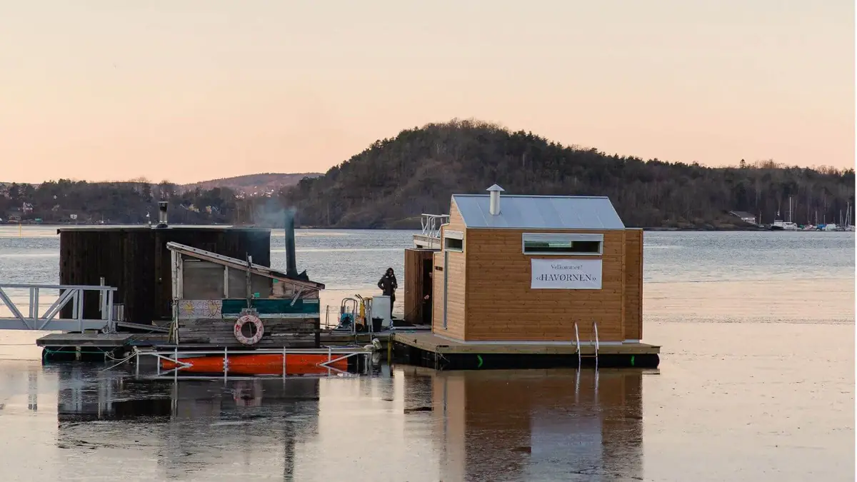 Floating sauna in thermally modified timber moored in Oslo harbour at dusk
