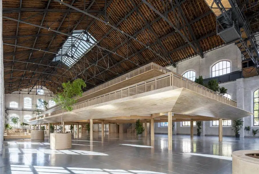 Nave histórica de Acciona Ombú con plantas escalonadas de madera bajo la cubierta original.