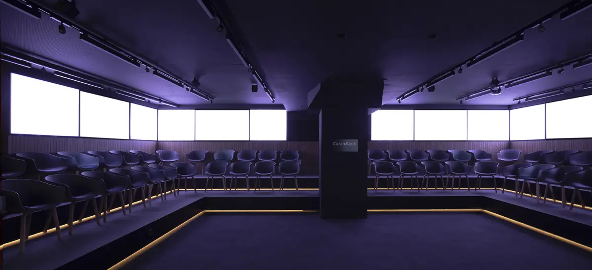 Auditorium with chairs on illuminated tiers and screens lit up all around the perimeter
