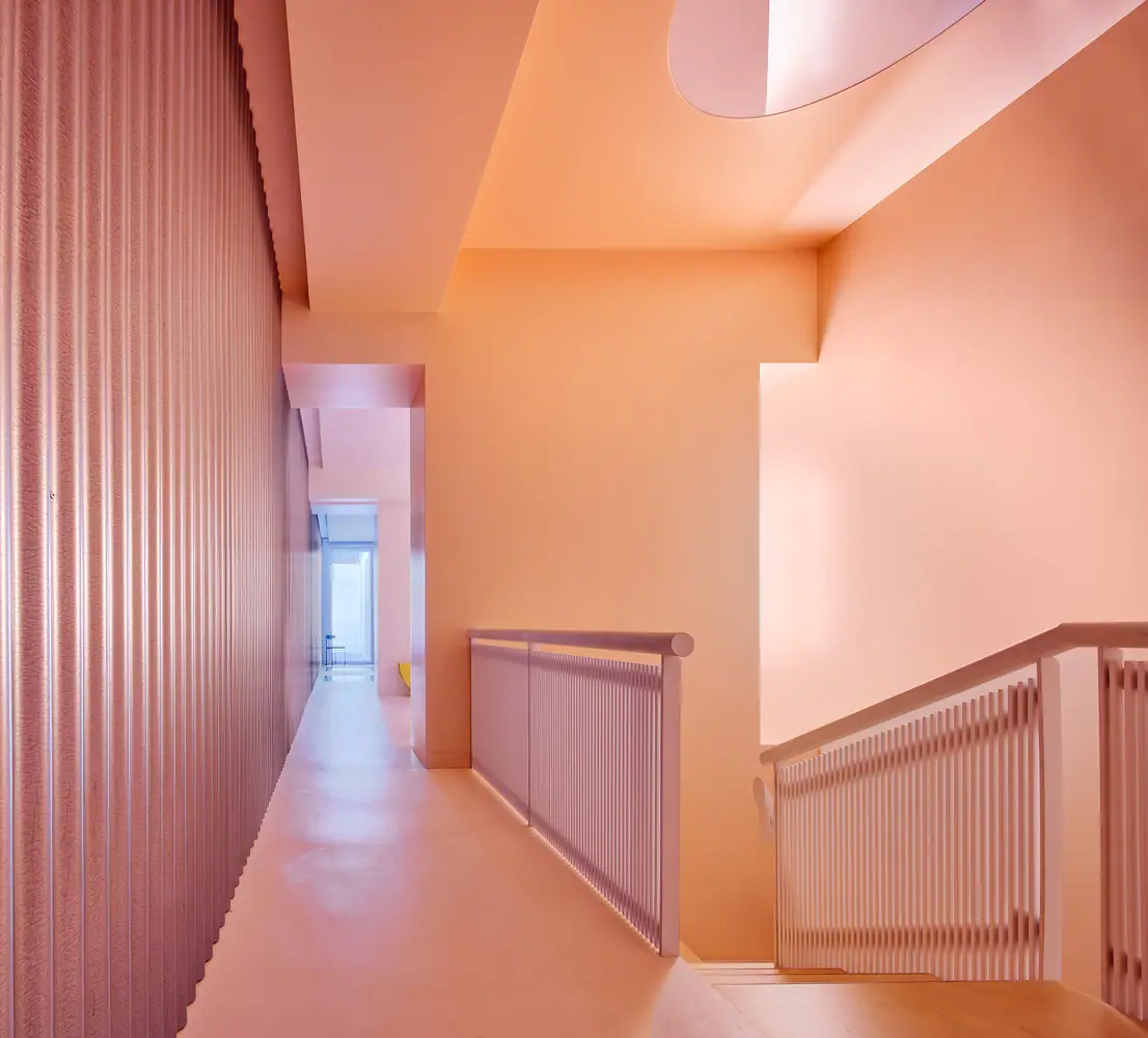 Staircase landing in pink and orange tones, with slatted balustrades, corrugated sheet metal and an oval skylight