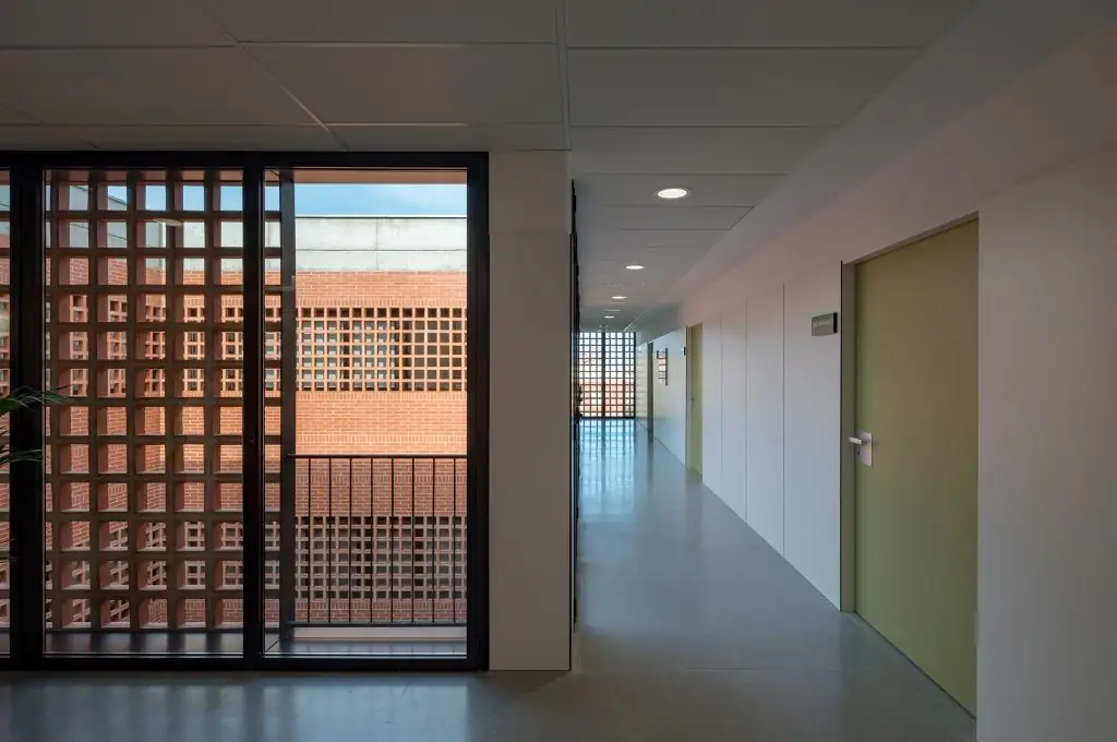 White corridor with consulting room doors and, on the left, a window with ceramic latticework onto the courtyard
