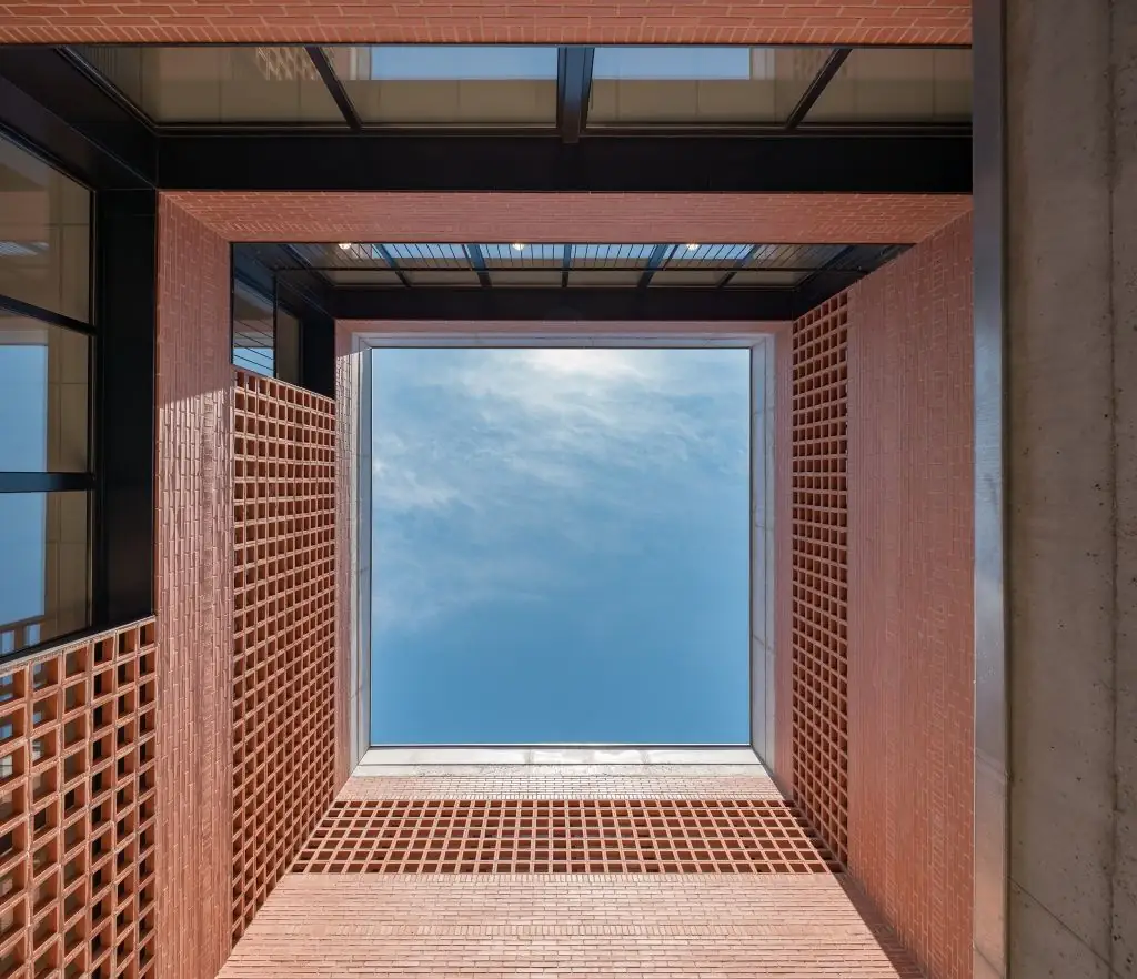 View up to the sky from the bottom of a courtyard of brick and ceramic latticework
