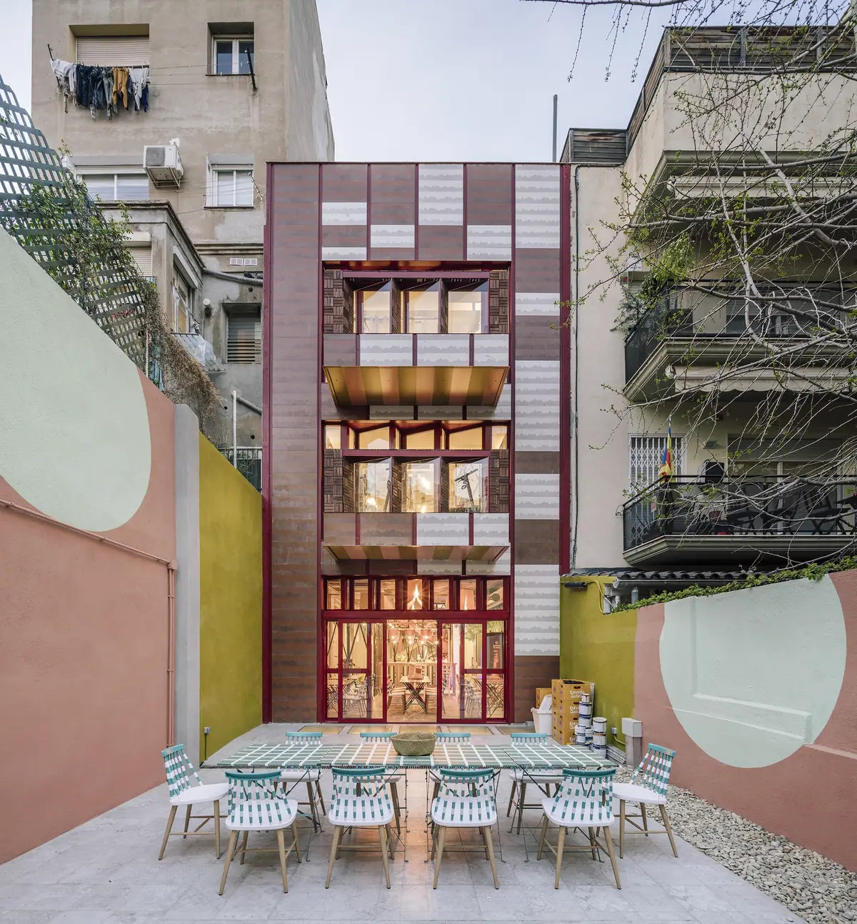 Rear façade of the building seen from the courtyard, with a long table and outdoor chairs